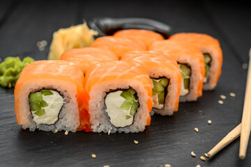 Sushi rolls with cheese philadelphia, salmon and tuna on a black background
