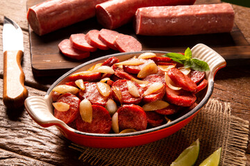 Smoked sausage with bread and onions on wood background. Snack appetizer calabrese sausage with onion.