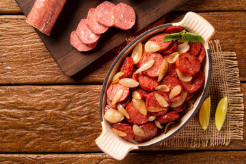 Smoked sausage with bread and onions on wood background. Snack appetizer calabrese sausage with onion.