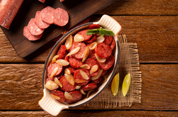Smoked sausage with bread and onions on wood background. Snack appetizer calabrese sausage with onion.