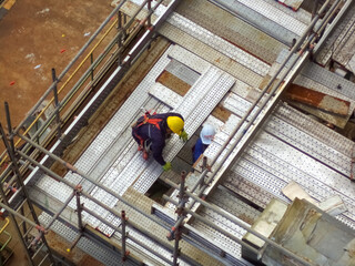Naklejka premium High building construction site with workers and steel bars.Group of workers working at high building construction site.and petrochemical plant