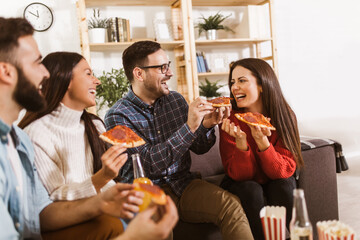 Group of young friends eating pizza in home interior.  Young people having fun together.