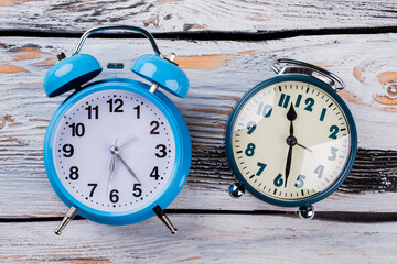 Two different vintage alarm clocks. Top view flat lay. White old wooden table.