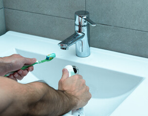 Man taking a toothbrush with a toothpaste