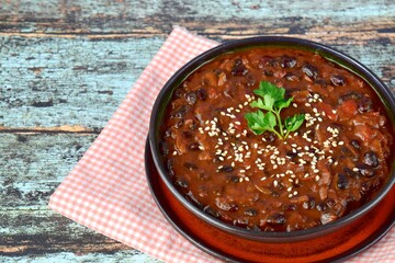 Homemade vegan chili black bean tomato soup garnish with sesame seeds and chopped parsley 
