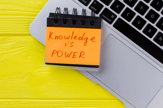 Top view laptop and knowledge is power slogan. Yellow wooden background.