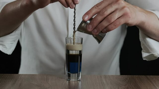 Preparing of Lexus Cocktail. Bartender pouring irish cream into glass