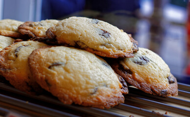 Gourmet chocolate chip cookies in a small pile just inside a bakery window