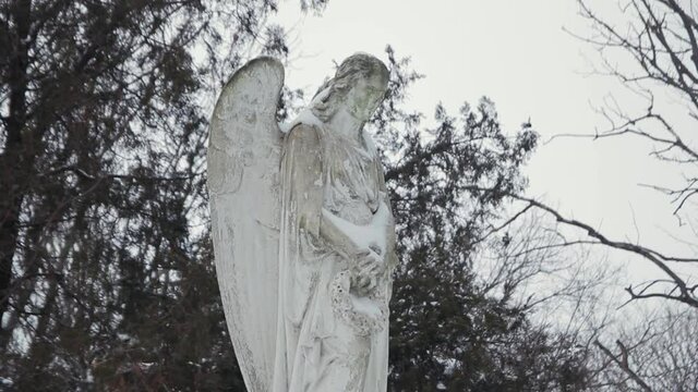 Stone statue of an angel in a cemetery in winter. Monument in the snow
