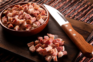 closeup of cubes of bacon on a rustic wooden board. Raw