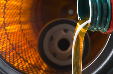 against the background of a burning filter, engine oil is pouring from the neck of the bottle into...