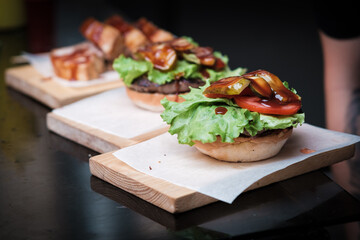 Burger Beef , tomatoes, red onions, cucumber and lettuce on black slate over dark background. Unhealthy food