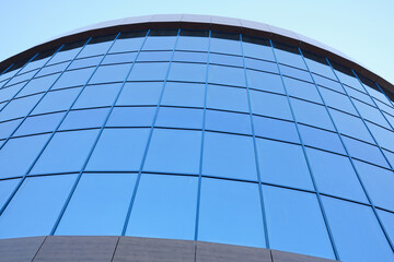 A low angle view of a modern building with blue glass windows. Office glass facade. Modern style office space.