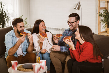 Group of young friends eating pizza in home interior.  Young people having fun together.