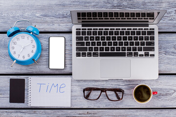 Time and office work concept. Laptop with alarm clock and cup of coffee on white wooden table.