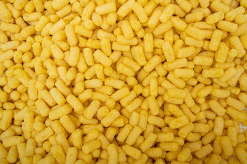 Top view on a pile of corn sticks. Background and texture. Crispy sticks for a children's breakfast.