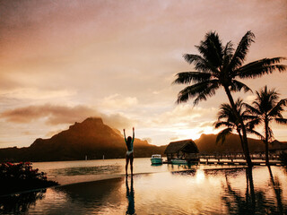 Sunset on the beach, young woman with hands in the air