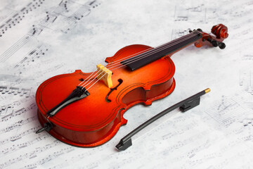 Fototapeta na wymiar miniature toy violoncello with a bow on the beautiful musical note background