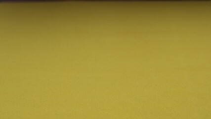 Mustard-colored material with a noticeable surface texture partially blurred