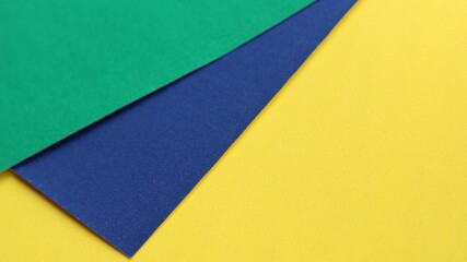 stationery background from sheets of blue, green and yellow thick paper with a dotted texture carelessly stacked on top of each other