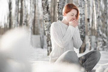 Beautiful young woman sitting in frozen park. Winter day on holiday, outdoor.