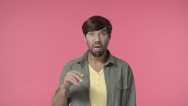 Annoyed and bored, rude young man mocking over boring person, mumbling and making blah blah gesture with grimace and dislike, bothered by uninteresting conversation, pink background