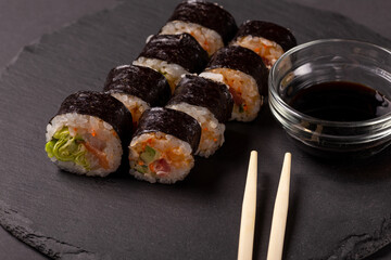 Sushi roll with wasabi ginger and soy sauce on a black background
