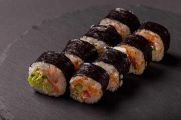 Sushi roll with wasabi ginger and soy sauce on a black background