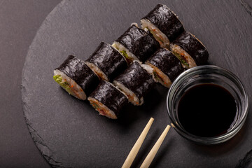 Sushi roll with wasabi ginger and soy sauce on a black background