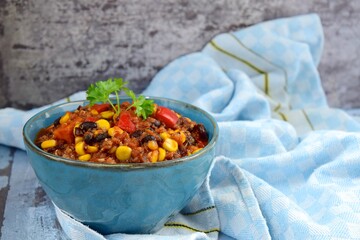 Black bean, quinoa, sweet potato, bell pepper and corn chili in a bowl garnish with parsley