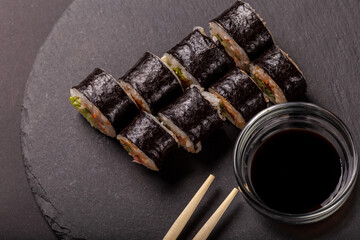 Sushi roll with wasabi ginger and soy sauce on a black background
