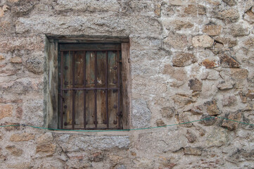 Fototapeta na wymiar stone wall with closed wooden window and metal fence