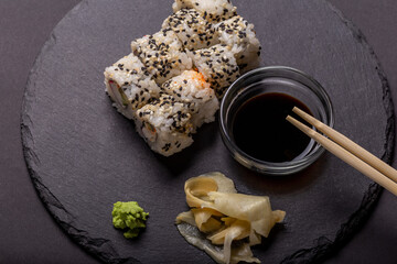 Sushi roll with wasabi ginger and soy sauce on a black background