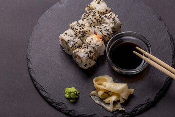 Sushi roll with wasabi ginger and soy sauce on a black background