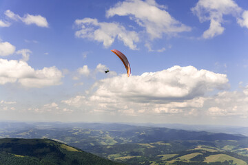 Paraglider soars in the sky against the background of blue mountains