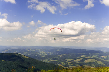 Paraglider soars in the sky against the background of blue mountains