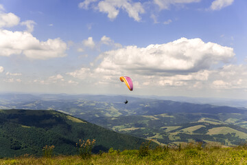 Paraglider soars in the sky against the background of blue mountains
