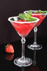Granite strawberry dessert in martini glasses on the black background. Closeup. Location vertical.