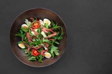 Fresh salad with roast beef meat, cherry tomatoes, arugula, quail egg