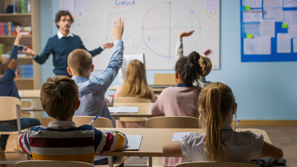 Caring Teacher Explains Lesson to a Classroom Full of Diverse Children. In School with Group of...