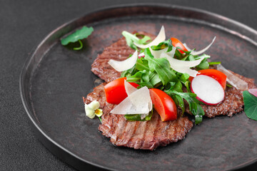Hot appetizer thin slices of grilled beef with cherry tomatoes, arugula