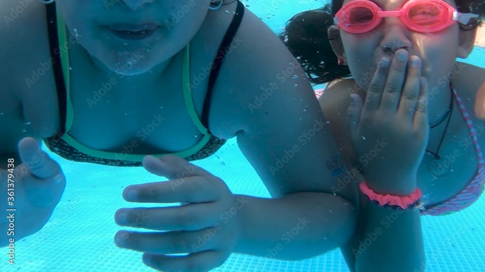 Wall mural group of four children going underwater in a beautiful pool