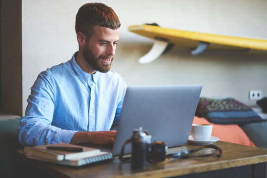 Handsome bearded male entrepreneur making remate job cooperating with colleague in online chat planning strategy for new startup project while keyboarding on laptop computer connected to 5G wireless