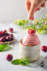 Bowl of cherry ice cream scoop with women hand and fresh berries on white background