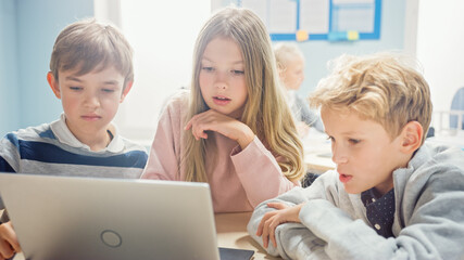Elementary School Classroom: Diverse Group of Brilliant Children Using Laptop Computer for Software...