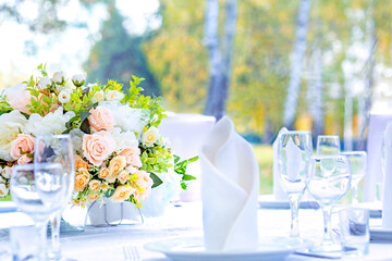 Wedding table with white tablecloth, outdoor setting, view of autumn bright yellow and orange trees