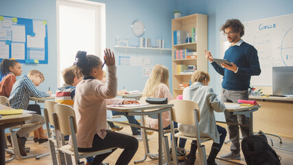 Caring Teacher Explains Lesson to a Classroom Full of Bright Diverse Children. In Elementary School...