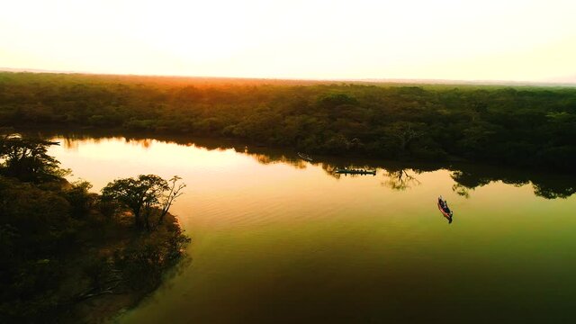 Wide Shot Above Serene Beautiful Amazon River With Boat Standing In The Middle And Orange Light Reflecting At Sunset In Cuyabeno National Park In Ecuador