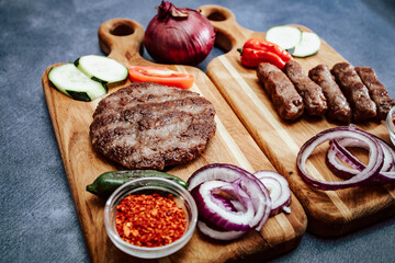 Wooden kitchen board with grilled meat, Turkish cevap and burger