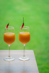 Top down view of cocktail glasses with orange, mango and red chilli exotic drinks in a British summer home garden. 